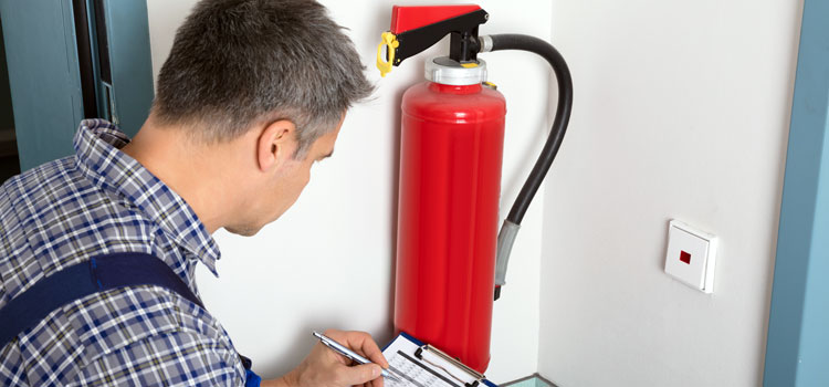 Photo of a worker carrying out a routine inspection of fire extinguishers in an office