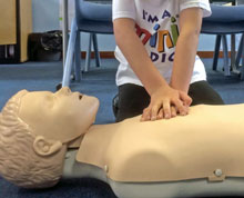 Image of a Mini Medics student practicing CPR on a dummy